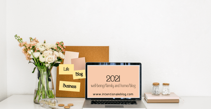 2021 year end reflection image of Flower vase, cork book and laptop on a desk with notes blog, family and home, blog and the year 2021