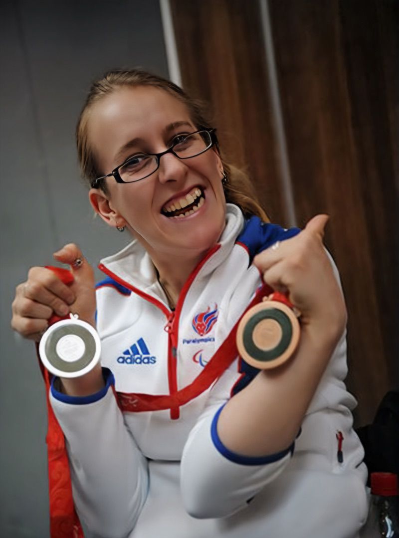 image of Dr Fran Whitaker a British gold medalist Paralympic Swimming, wearing a big smile, holding 2 medals in both hands